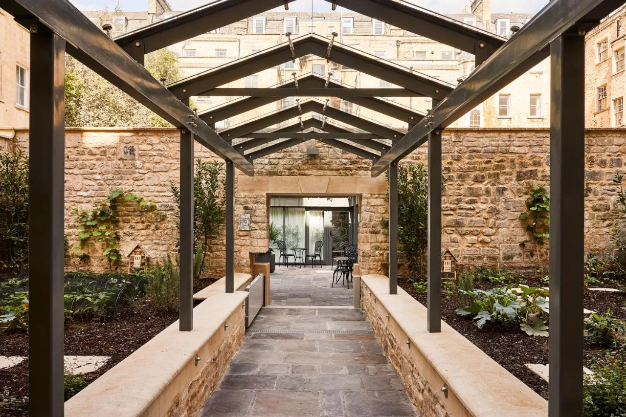 an external view of a brick building with a wooden pergola at Hotel Indigo - Bath by IHG in Bath