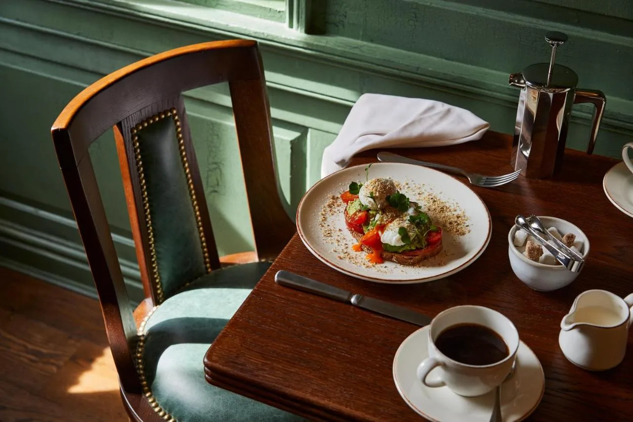 a table with a plate of food and a cup of coffee at Hotel Indigo - Bath by IHG in Bath